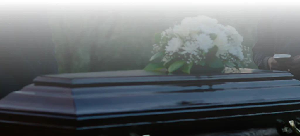 Coffin with a white floral arrangement on top.