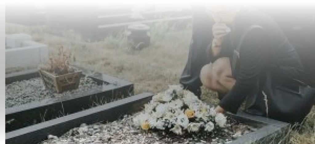 A women kneeling and placing flowers at a gravesite.
