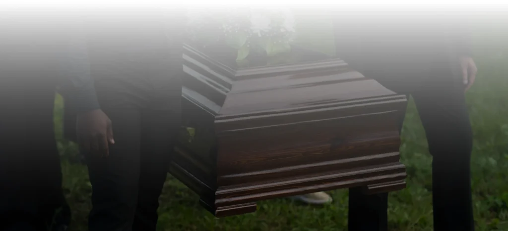 Person carrying a coffin with a floral arrangement.