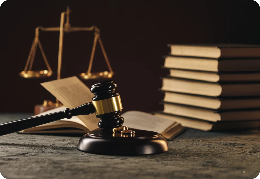 Golden scale of justice, gavel, and stack of books on a wooden surface.