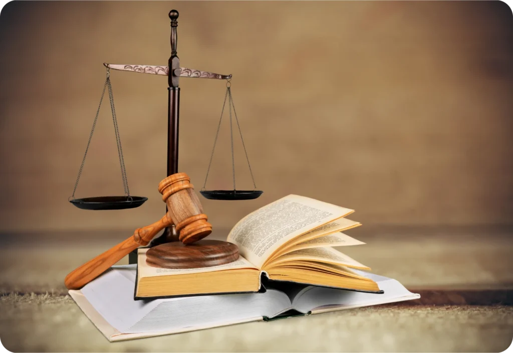 Golden scale of justice, gavel, and stack of books on a wooden surface.