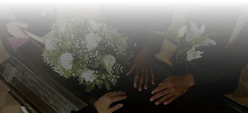 People placing floral arrangements on a coffin.
