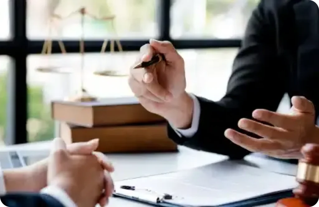 Two people discussing with a gavel and scale of justice on a desk.