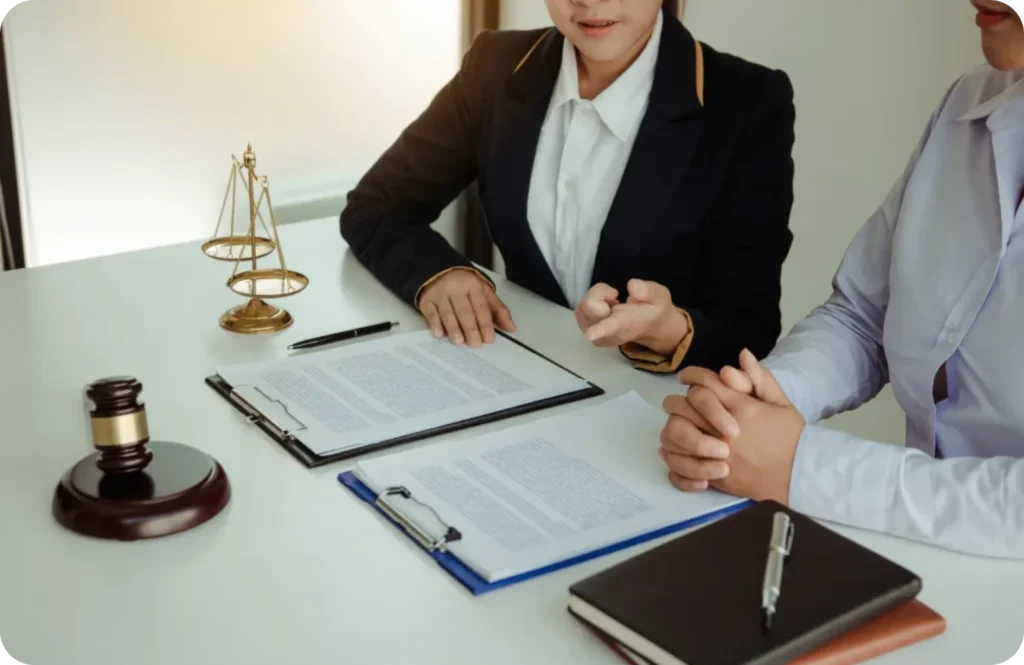 Two people discussing with a gavel and documents on a desk.
