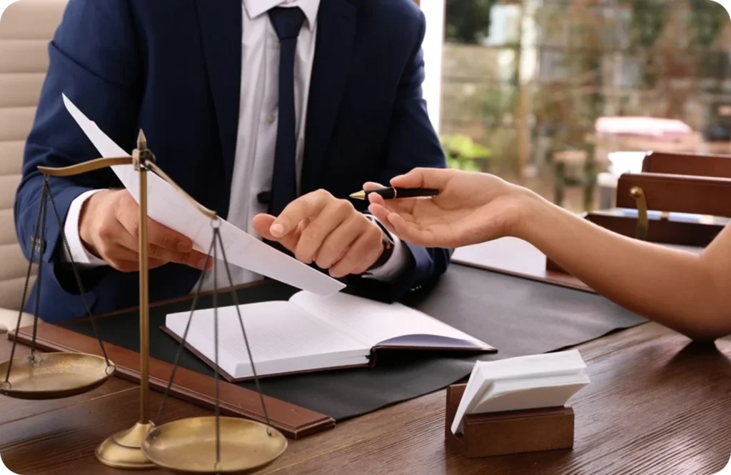 Two people discussing over a document at a desk.