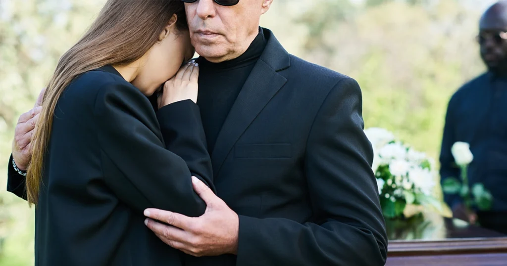 Grieving family members embracing at funeral after wrongful death