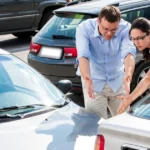 Man and woman examining damage between two cars after a parking lot accident.