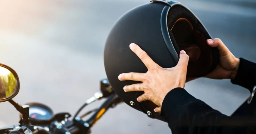 Person holding a motorcycle helmet beside a bike.