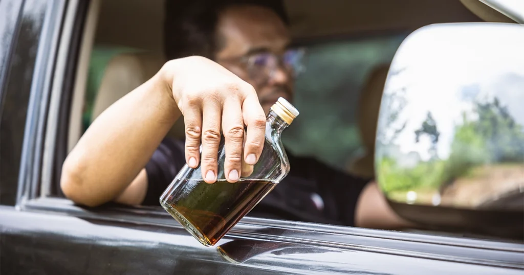 Driving under the influence with a liquor bottle.