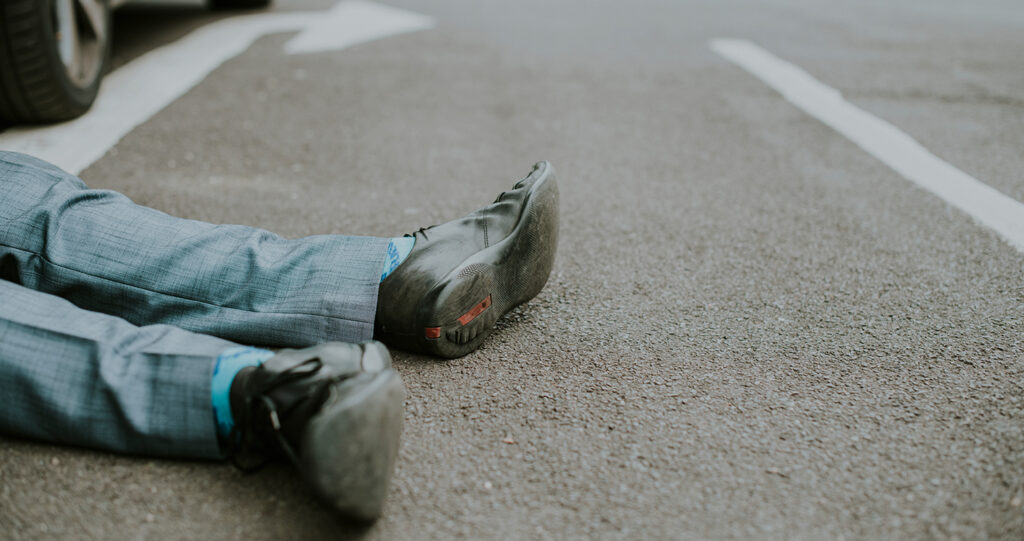A person in a suit lying on asphalt after accident.