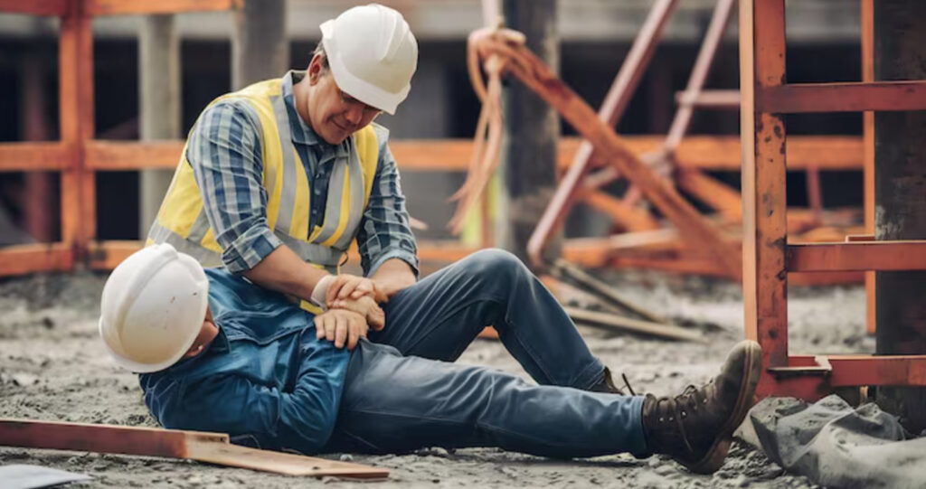 Construction worker assisting an injured colleague on a job site.