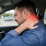 Man sitting in a car grips the back of his neck in pain, with a red highlight showing a whiplash injury.