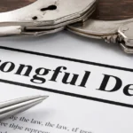 Close-up of a “Wrongful Death” document with handcuffs and a pen on a desk.