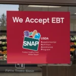 Storefront window displaying a red sign indicating acceptance of EBT and USDA SNAP benefits.