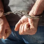 Close-up of a person's hands handcuffed behind their back.