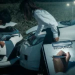 Insurance agent filling form while drivers inspect damaged car accident.
