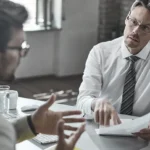 Lawyer and doctor discussing documents during a formal meeting.